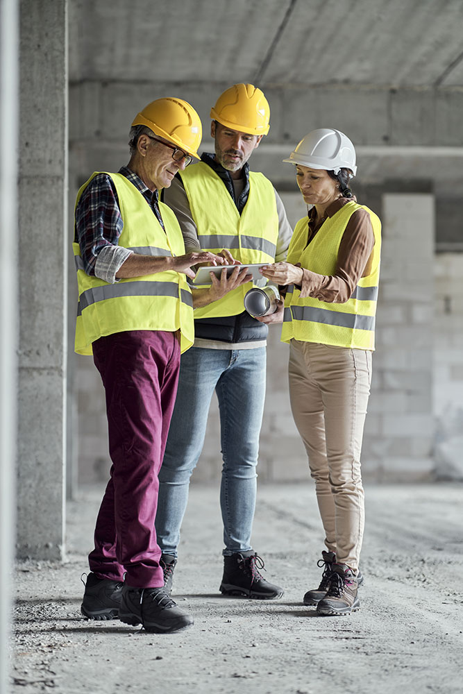 Tres ingenieros caucásicos discutiendo juntos en el sitio de construcción Imagen de Tres ingenieros caucásicos discutiendo juntos en el sitio de construcción